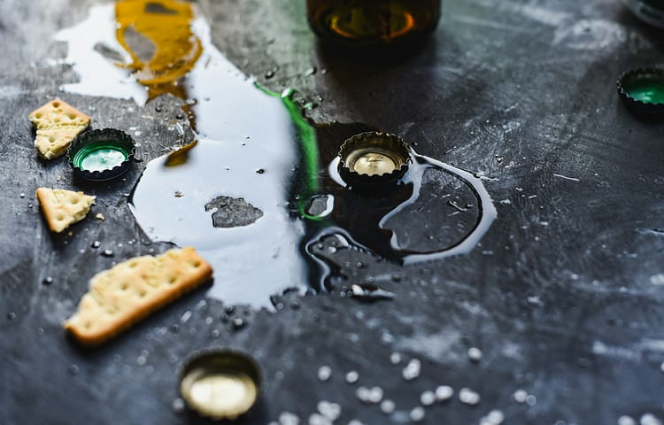 Spilled beer on a black background with beer bottle caps